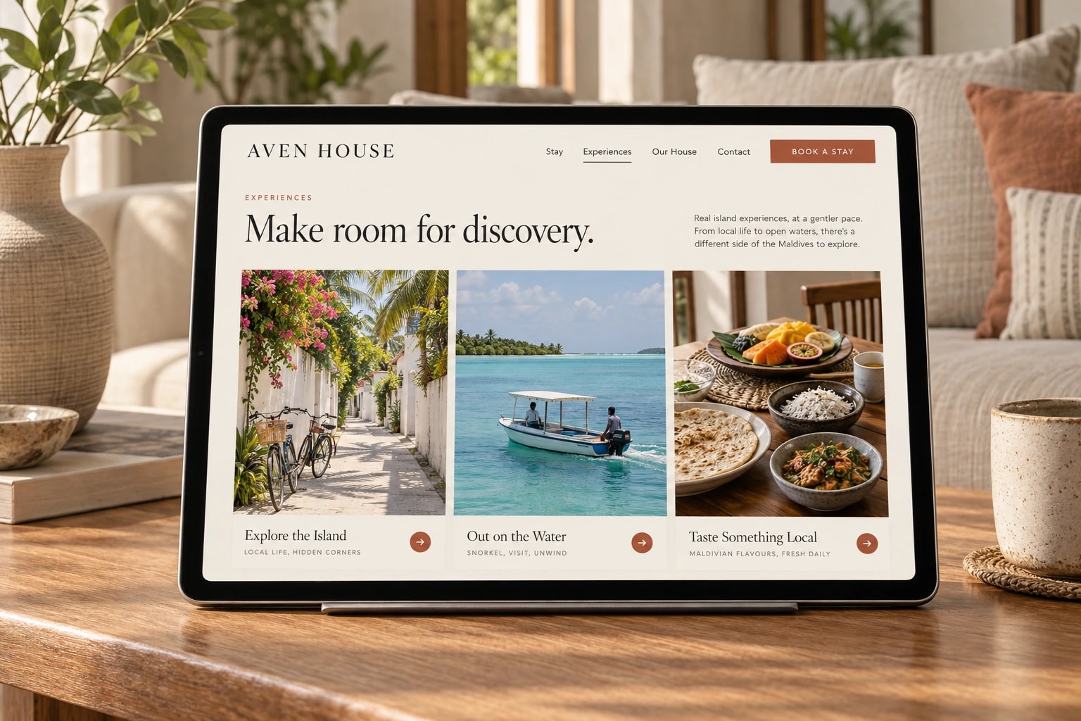 A tablet shows the Aven House experiences page, headed “Make room for discovery.” with three photos: an island lane, a boat on turquoise water and local food.