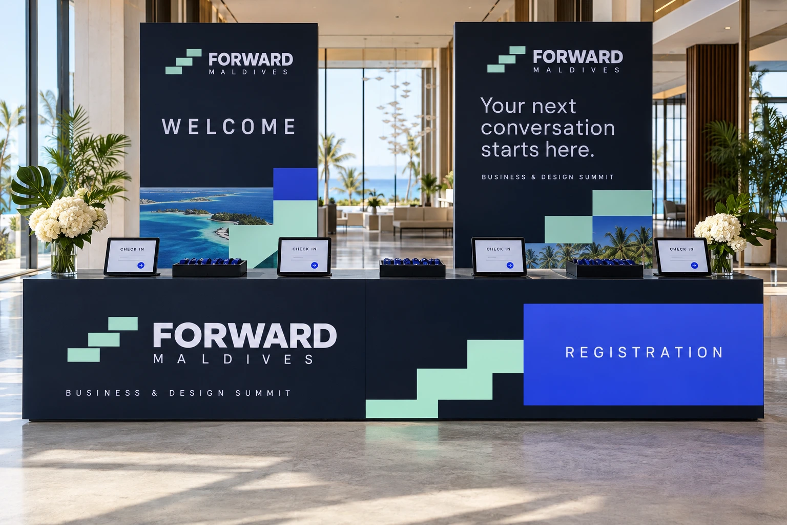 A Forward Maldives registration desk in navy, mint and blue, with “WELCOME” and “Your next conversation starts here.” panels, check-in tablets and white flowers in a bright lobby.