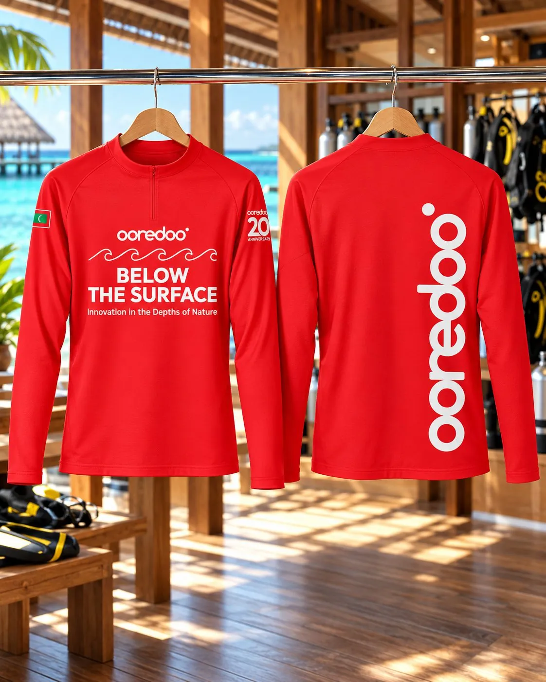 Two red Below the Surface rash guards on hangers, front and back, in a dive shop.