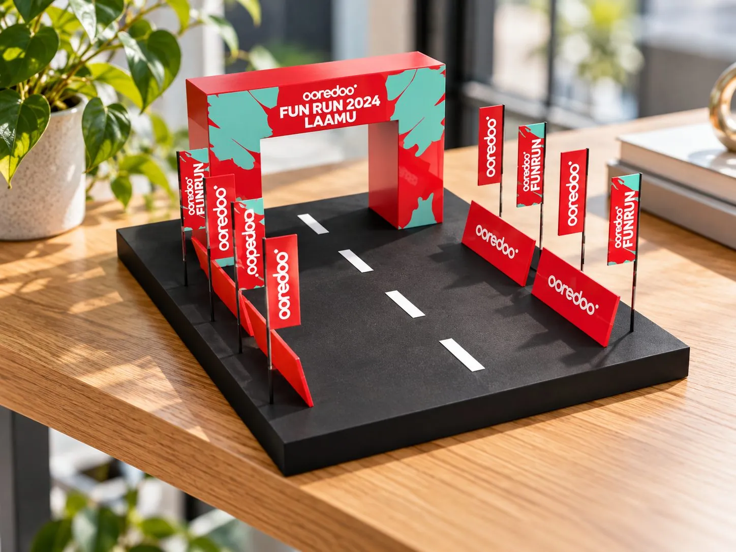 Scale model of the Fun Run 2024 Laamu start arch, with red flags lining a black road.