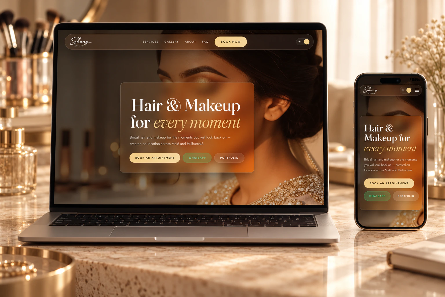 Shany Artistry home page on a laptop and a phone, on a dressing table with makeup brushes.